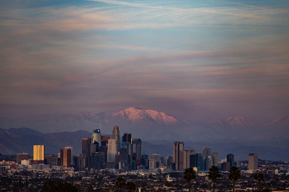 Breathtaking view of Los Angeles skyline against snowcapped mountains at twilight, capturing the urban landscape.